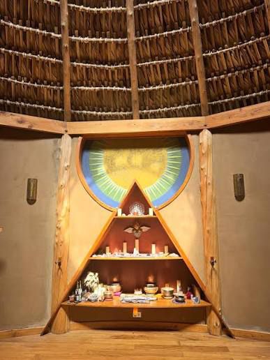 Altar triangular con sol naciente, velas, cuencos y ofrendas en la maloca