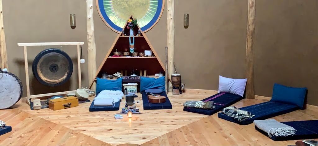 Interior de la maloca con círculo de colchones, mantas y altar central